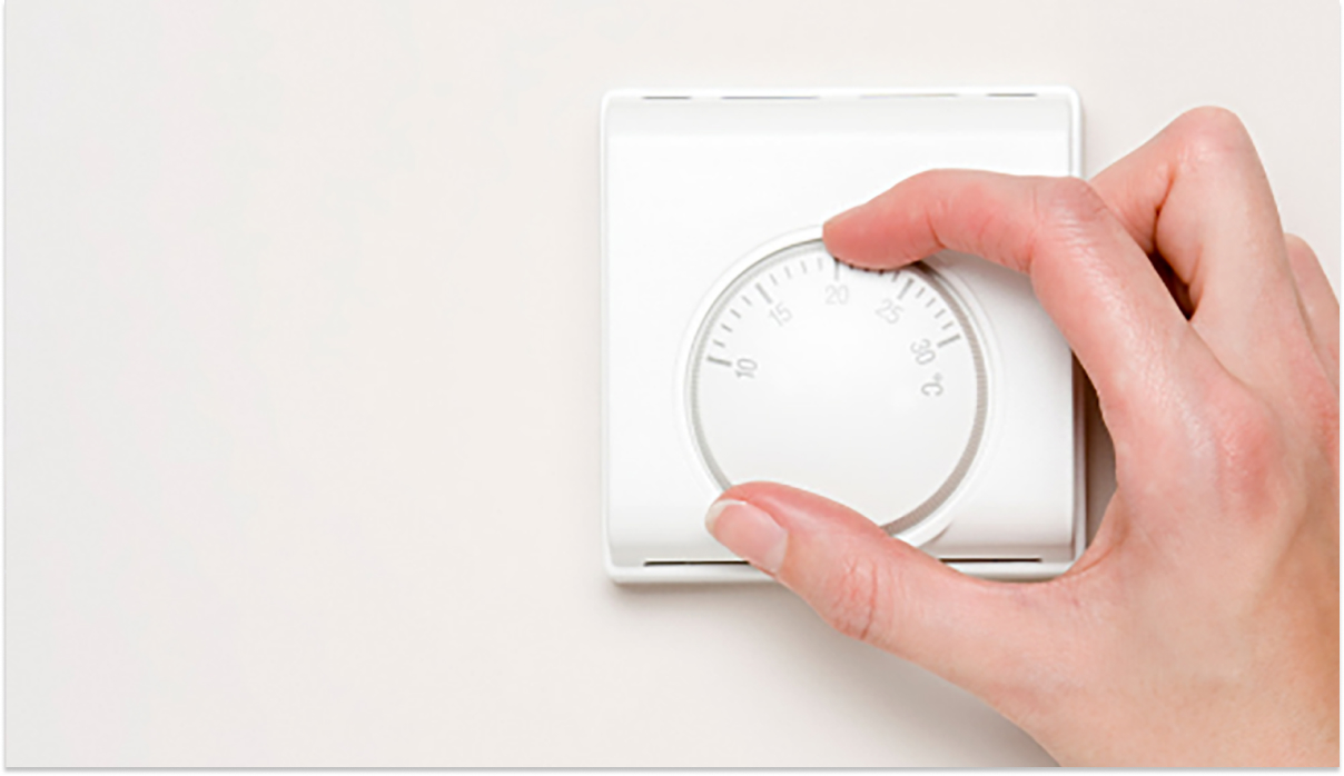 Hand adjusting thermostat to save energy and reduce heating and cooling costs in healthcare facilities