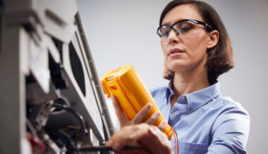 Female healthcare worker with glasses examining prescription medication bottle in clinical setting