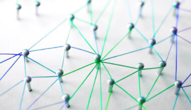 Network of connected blue and green lines with circles at intersections on white background