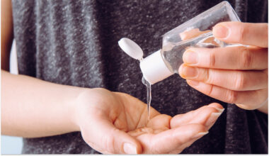Hands using sanitizer from a clear bottle, promoting hygiene and healthcare safety practices.
