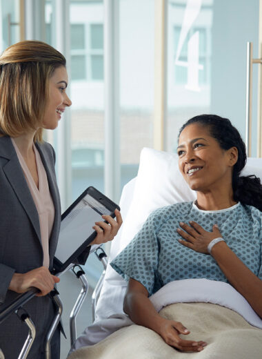Patient and healthcare worker discuss care plan in hospital room, both smiling