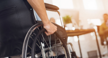 Person in wheelchair in office setting, symbolizing healthcare accessibility and support services.