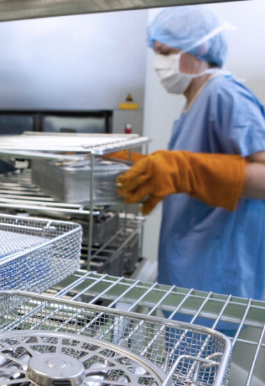 Technician loading hospital surgical instrument sterilization trays in medical facility