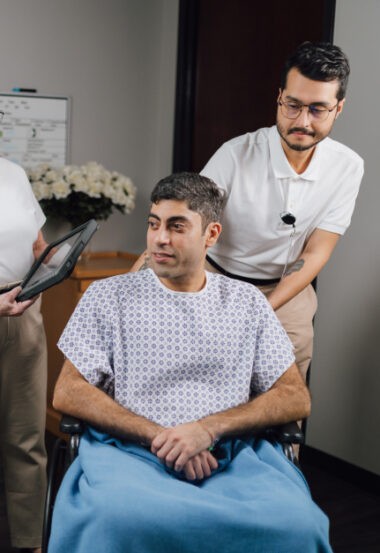 Patient in hospital gown receiving care from healthcare provider in office setting