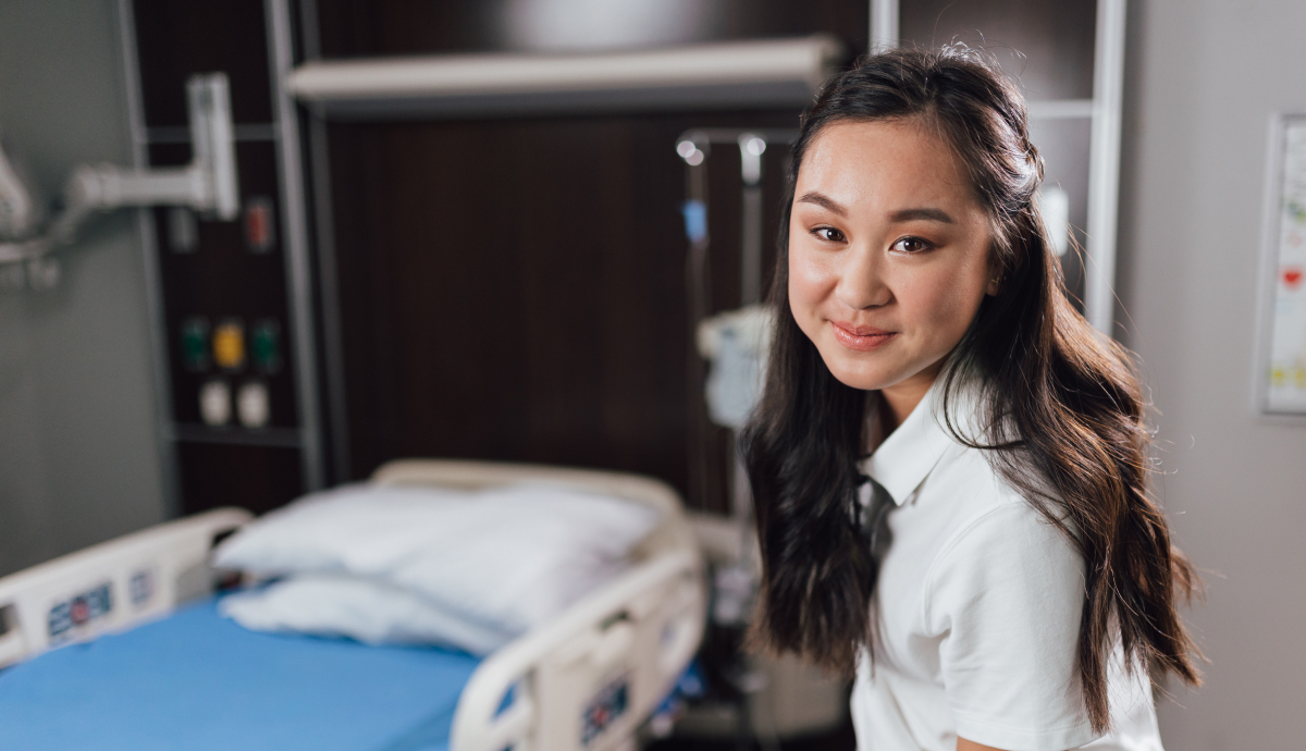 Smiling Asian female healthcare worker in hospital room