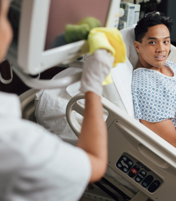Young male patient smiles at nurse while sitting in hospital bed during interaction