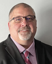 Middle-aged businessman with glasses, beard and checkered shirt and red tie smiling at camera