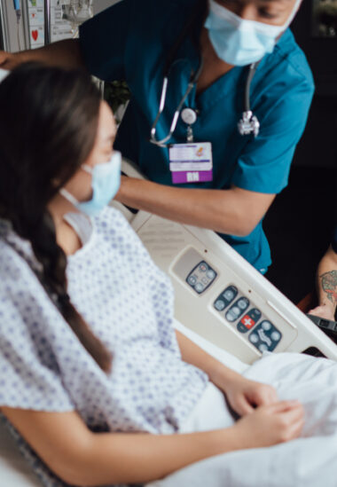 Patient and nurse with medical equipment in hospital room