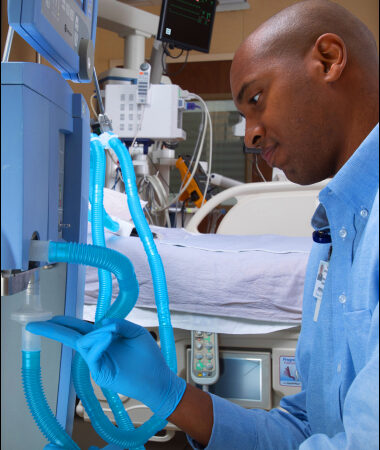 Focused medical professional adjusting equipment in a hospital room with modern technology.