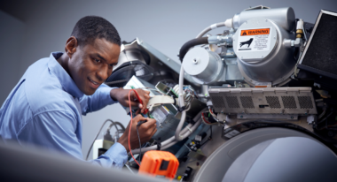 Concentrated technician repairing complex machinery with warning label visible