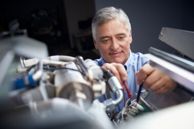 Alt text: Smiling senior male technician repairing medical equipment in a healthcare facility