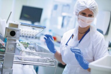 Medical professional in protective gear and mask working with laboratory equipment and samples