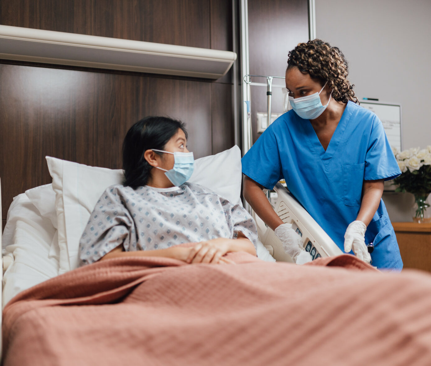 Nurse attending to patient in hospital room, providing compassionate care and support.