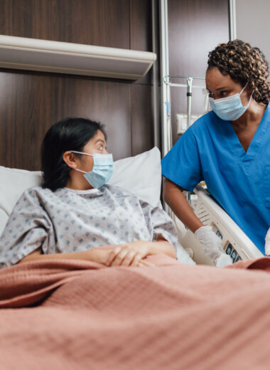 Nurse attending to patient in hospital room, providing compassionate care and support.