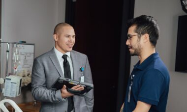 Two smiling hospital workers discussing medical equipment during rounds