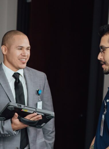 Two smiling hospital workers discussing medical equipment during rounds