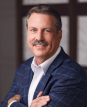 Professional, smiling man with gray hair and mustache wearing blue patterned jacket and white shirt