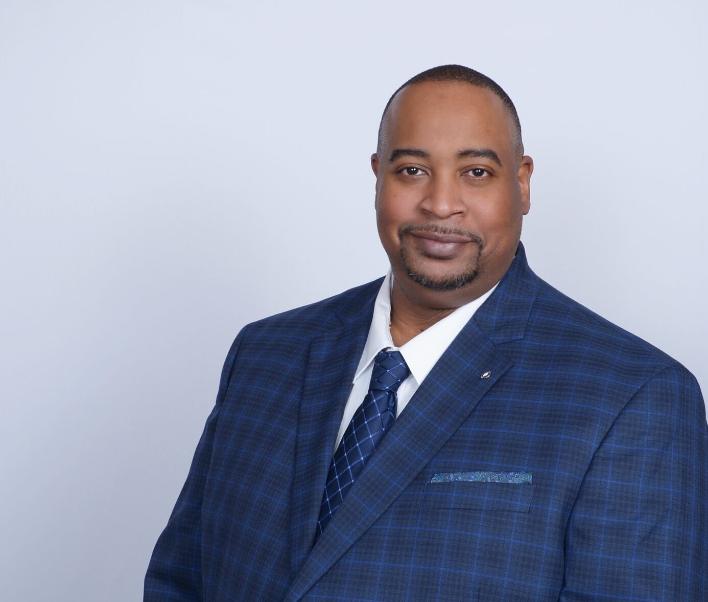 Smiling African American businessman wearing blue checkered suit and tie, studio portrait headshot