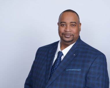 Smiling African American businessman wearing blue checkered suit and tie, studio portrait headshot