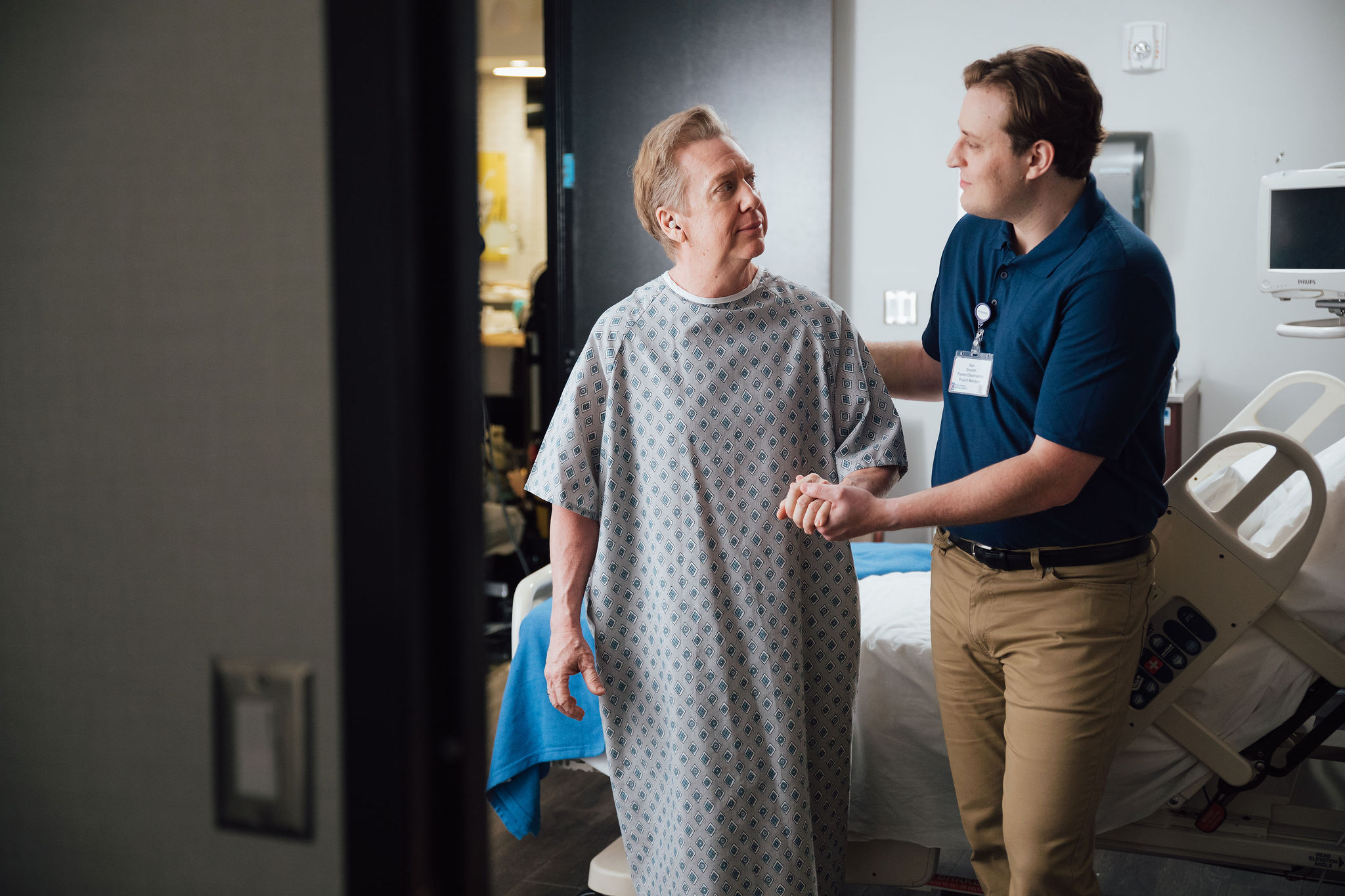 Elderly patient and hospital staff member talking in hospital room with medical equipment