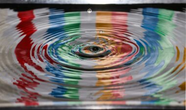 Colorful water ripple with concentric circles in red, blue, green and yellow hues, closeup view