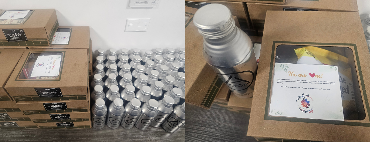 Stacks of boxed meals and aluminum water bottles are neatly arranged on a table. The meal boxes have a clear window showing snacks inside, along with a message card that reads, 